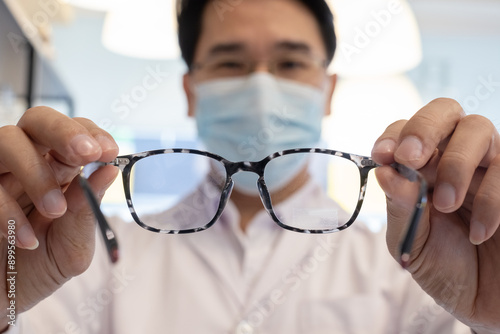 Close up eyeglasses in hands, Man professional optician selling holding spectacles in clinic, View through the back.