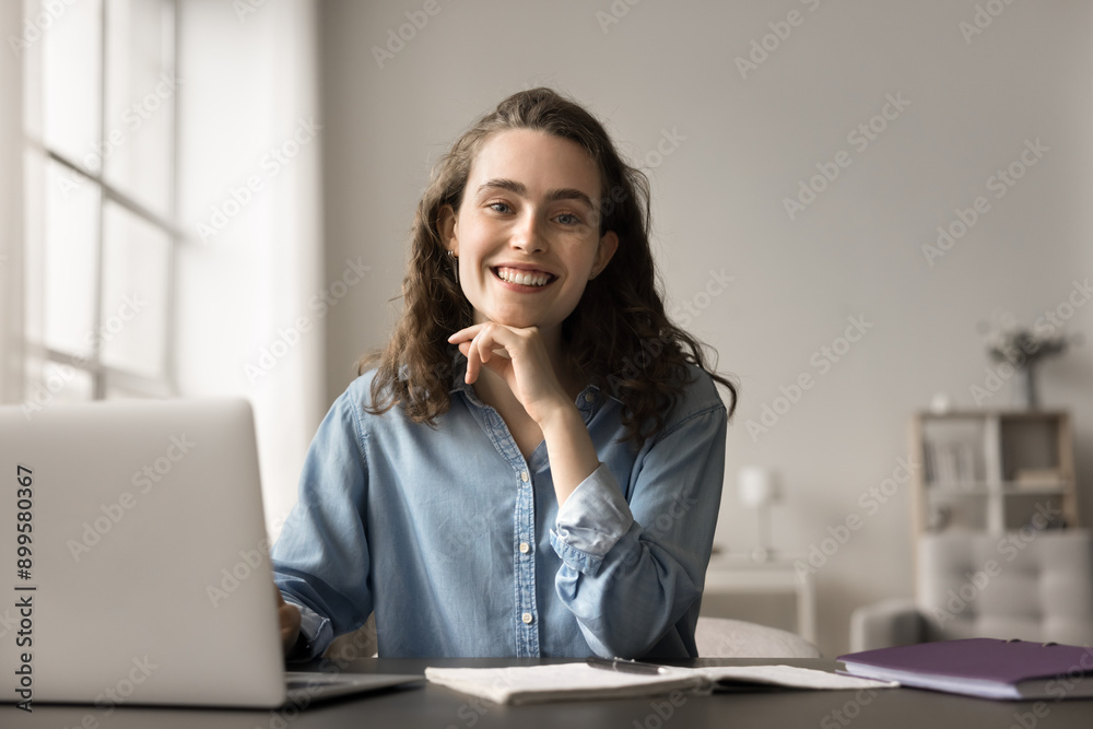 Portrait of smiling young woman sitting at table with laptop working or studying on-line. Gain new knowledge using education resources, do freelance job remotely feel satisfied. Tech, learn, workflow Portrait of smiling young woman sitting at table with laptop working or studying on-line. Gain new knowledge using education resources, do freelance job remotely feel satisfied. Tech, learn, workflow