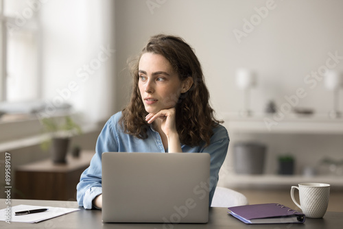 Woman sit at desk with laptop, look into distance, having dreamy mood, distracted from telework, studying or freelance. Young gen and modern technology, e-learning online, educational platform user