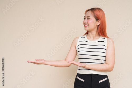 Portrait of Beautiful Asian Woman Showing Copyspace Against Plain Background