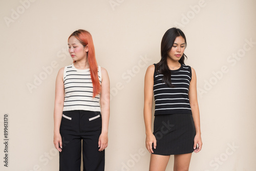 Portrait of Two Beautiful Woman Outdoors Looking Down Studio Shot Against Plain Background