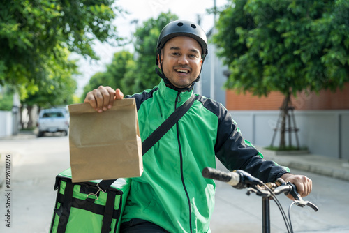 Portrait Rider food delivery man wearing green uniform and helmet cycling a bicycle the food service to customer. Happy delivery man with green backpack shipping of goods to customers. photo