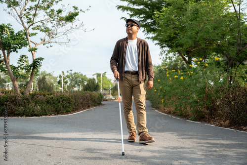 Foto Young blind man walking in city with walking stick