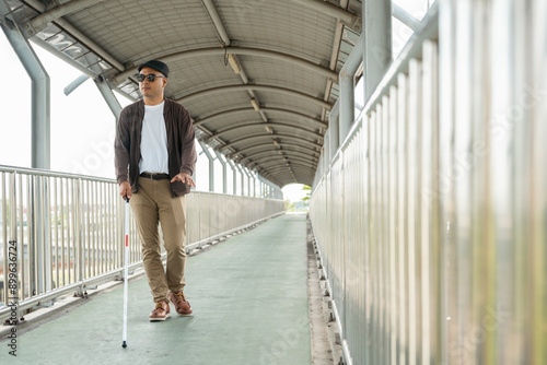 Wallpaper Mural Young blind man walking in city with walking stick. Visually impaired man difficult to traveling on the road wearing sun glasses Cross the road cross the footbridge Torontodigital.ca