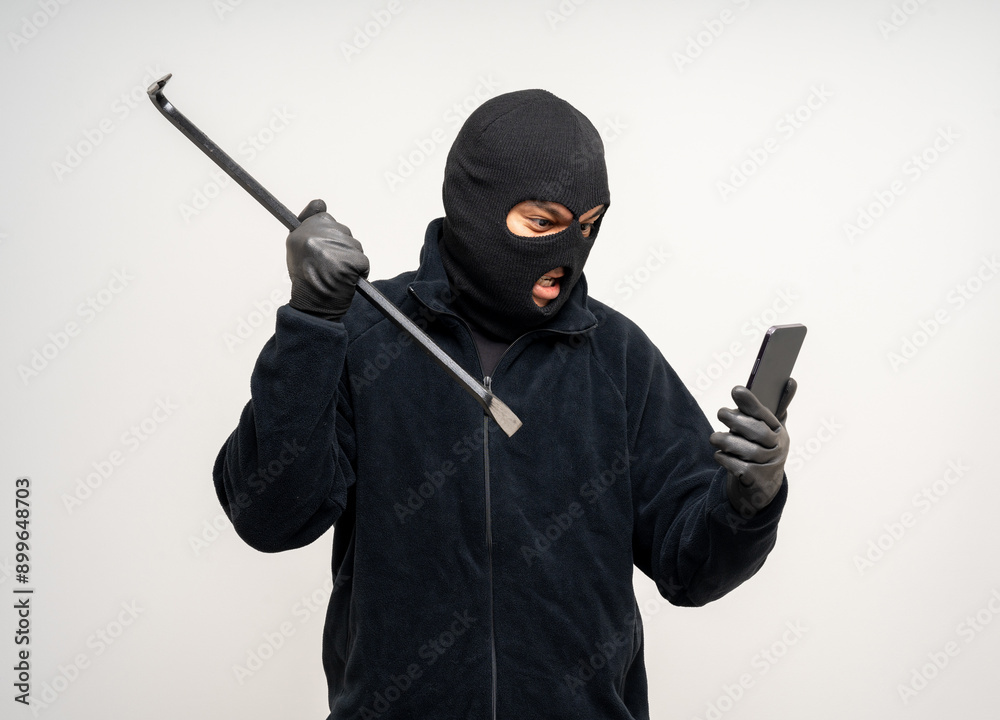Thief in uniform black jacket various pose on isolated background. The Robber terrorism criminal escapes with balaclava and crowbar entering a house for stealing Housebreak Thief in uniform black jacket various pose on isolated background. The Robber terrorism criminal escapes with balaclava and crowbar entering a house for stealing Housebreak