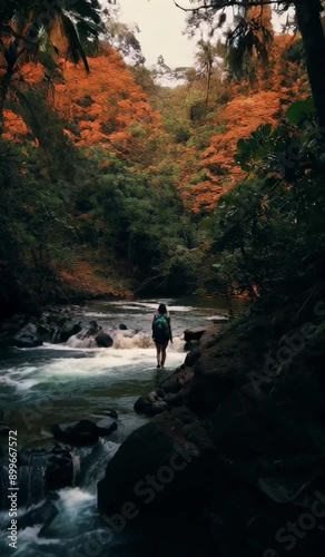 Woman with backpack looking at a river, styled in mysterious jungle, dark orange and light emerald colors, secluded environment, nature inspired imagery