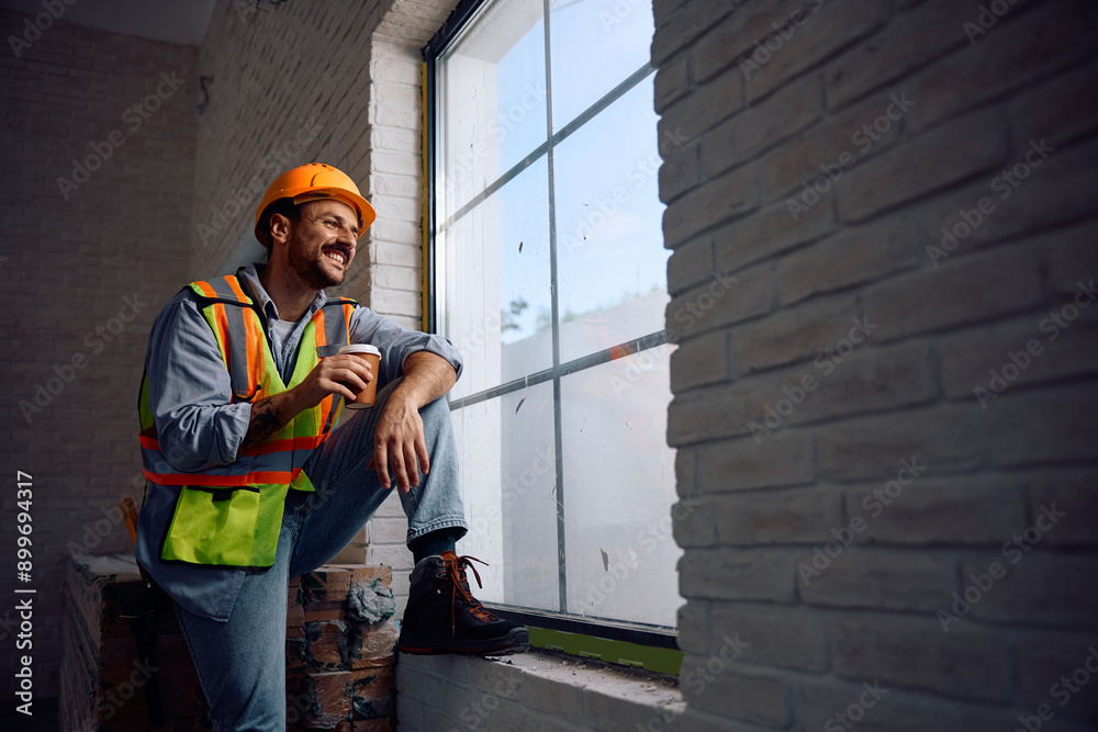 Happy worker having cup of coffee while taking break at construction site. Happy worker having cup of coffee while taking break at construction site.