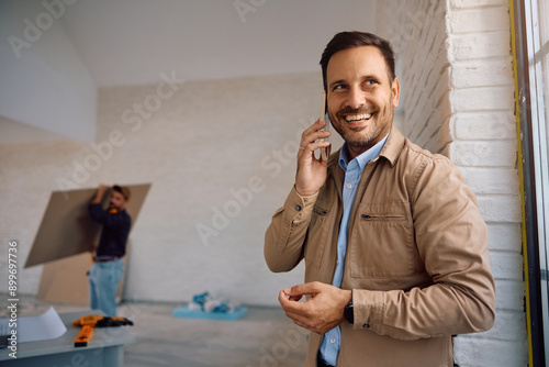 Happy home owner talking on cell phone during home renovation process. photo