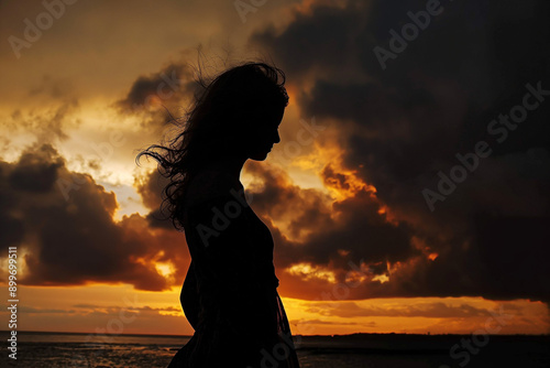 Silhouette of Woman Against Fiery Sunset Sky: Dramatic Contrast at Ocean's Edge