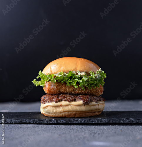 Gourmet chicken burger with cheese and veggies. Juicy delicious hamburger on darkmood picture for restaurant decoration, poster.
 photo