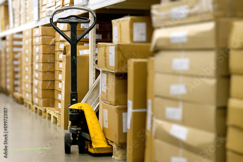 Manual Pallet Jack Waiting Amidst Cardboard Boxes in a Warehouse Aisle