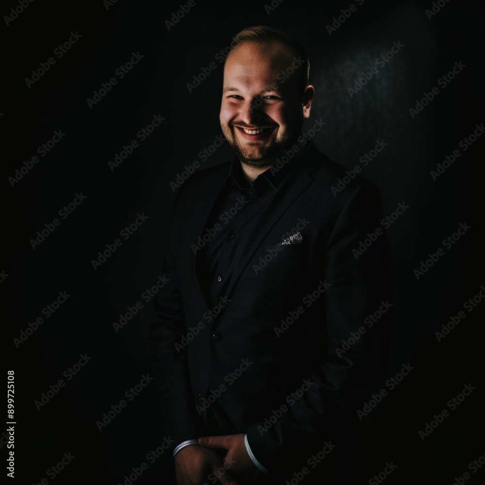 Smiling Male Executive in Minimalistic Portrait Against Dark Background Smiling Male Executive in Minimalistic Portrait Against Dark Background