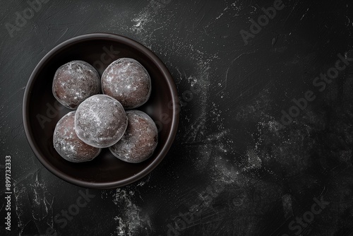 Chocolate-flavoured mochi in a plate on matte black background with copy space. Traditional Japanese rice cake confection.