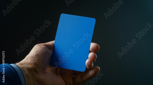 A soccer referee holding a blue card. 