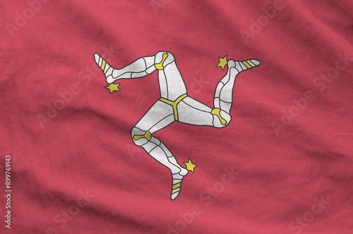 Isle of Man flag depicted on folded wavy fabric of old cloth close up photo