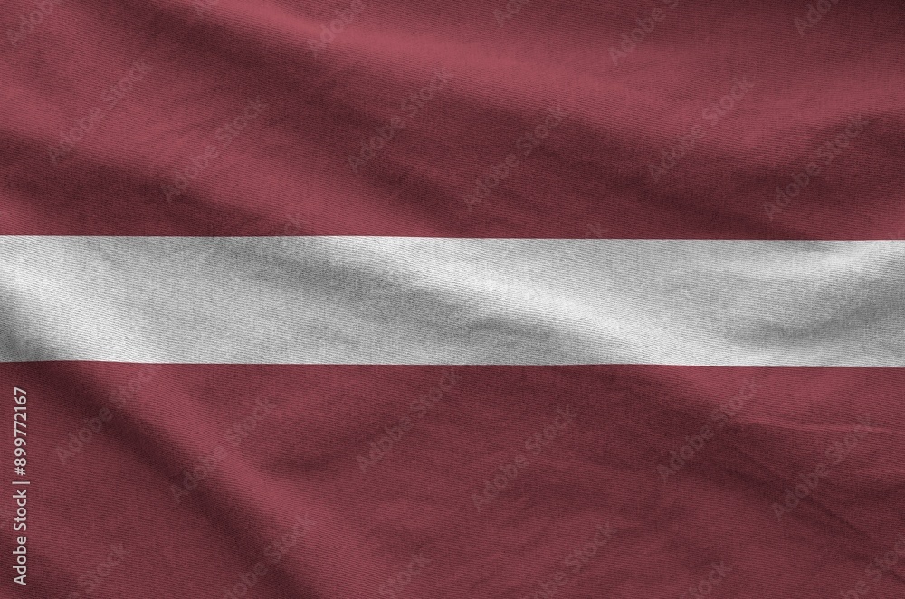 Latvia flag depicted on folded wavy fabric of old cloth close up Latvia flag depicted on folded wavy fabric of old cloth close up