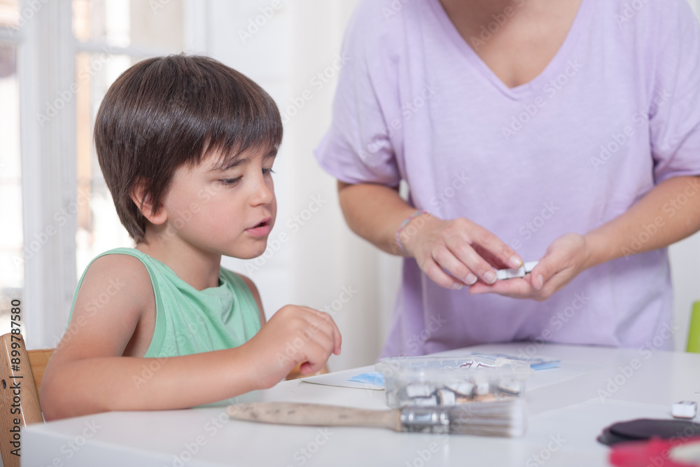 A boy prepares to make a handicraft while a woman prepares the material to make it. A boy prepares to make a handicraft while a woman prepares the material to make it.