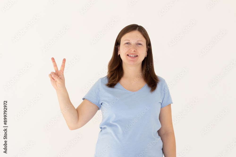 Young caucasian smiling happy friendly woman in stylish casual blue t-shirt show victory v-sign gesture isolated on white background studio portrait People lifestyle concept Young caucasian smiling happy friendly woman in stylish casual blue t-shirt show victory v-sign gesture isolated on white background studio portrait People lifestyle concept