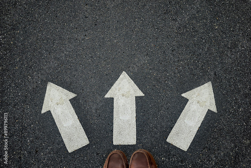 Foot of businessman step on 3 arrow direction; concept of decision 