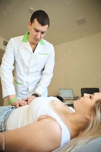 Physician performing abdominal palpation of adult female patient