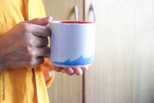 He is holding a white cup mockup in his hand
