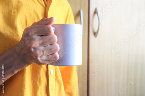 He is holding a white cup mockup in his hand
