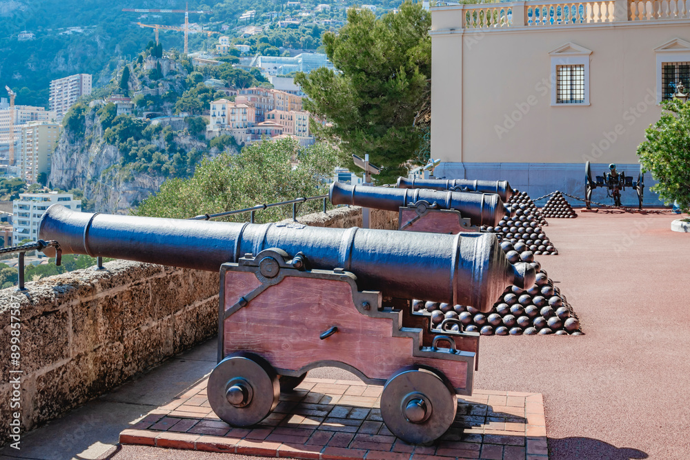 Monaco. Monte Carlo. A historic cannon and pyramid of cannonballs overlooking a coastal city with ocean and urban landscape.