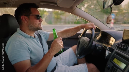 drink and drive. man drinks alcohol while driving a car. Illegal drunk driving. 