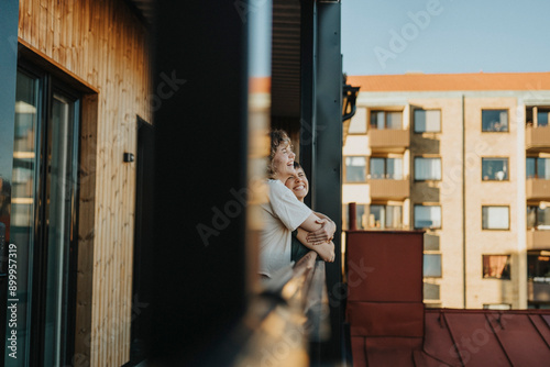 Happy lesbian woman embracing girlfriend while standing in balcony photo