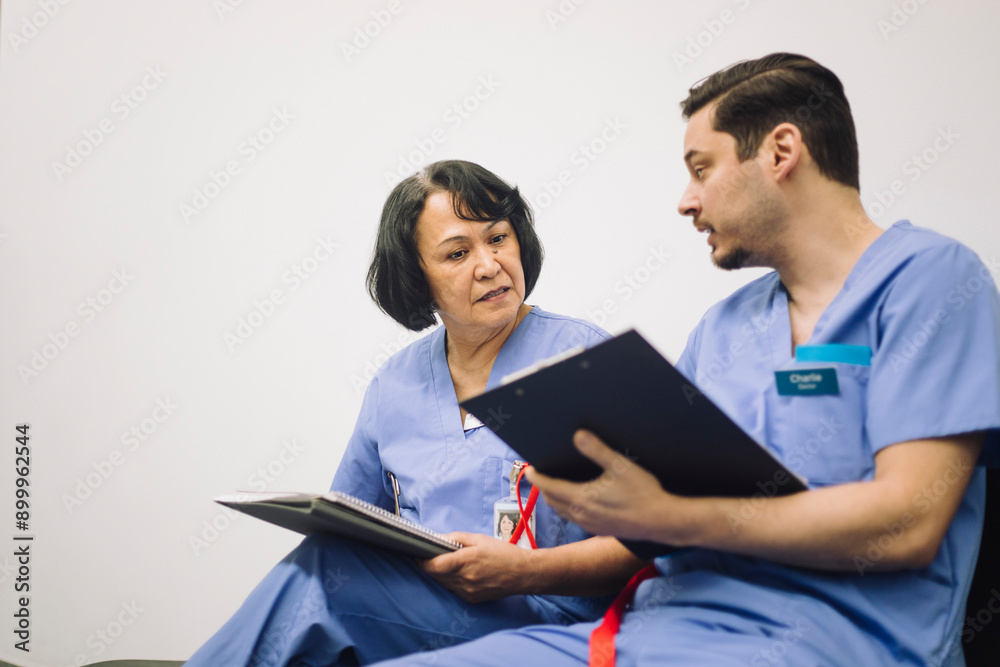 Mature male medical professional discussing with senior female doctor in hospital Mature male medical professional discussing with senior female doctor in hospital