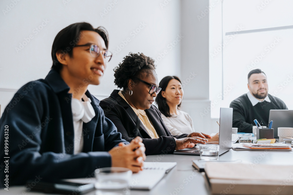 Mature businesswoman working on laptop while sitting with coworkers in office Mature businesswoman working on laptop while sitting with coworkers in office