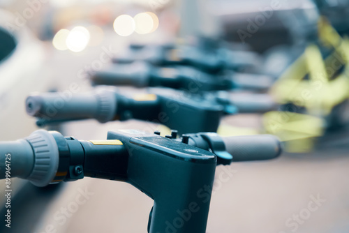 A line of electric scooters with electric blue steel casing pipes parked on the roadside
