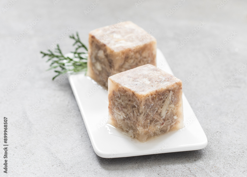 Jellied meat in the shape of a cube. On a plate. Close up