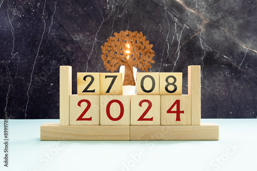 Wooden block calendar with the date August 27 and spikelets of wheat on a beige concrete background.