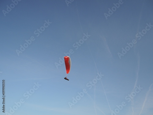 A paragliding pilot soaring high above the ground, enjoying the freedom of flight and breathtaking views, embodying the thrill and joy of this adventurous aerial sport. photo