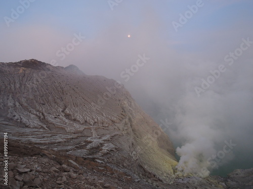 Billede på lærred Panoramic view of Mount Ijen, an active volcano in Indonesia, with sulphur smoke rising and fogs laying around
