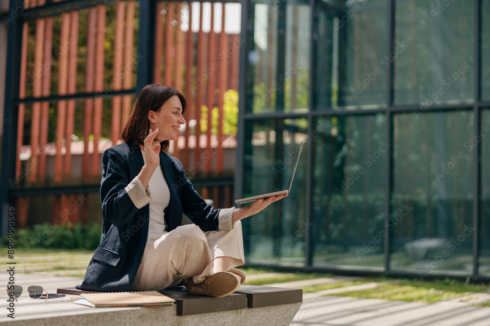 A young professional woman is having a virtual meeting outdoors using her laptop A young professional woman is having a virtual meeting outdoors using her laptop