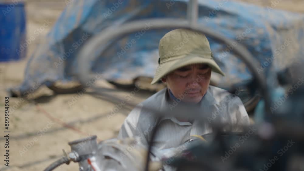 slow motion Vietnamese mechanic with a big hat working repairing the engine of a boat slow motion Vietnamese mechanic with a big hat working repairing the engine of a boat