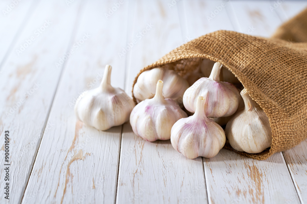 fresh garlic in a sack on a wooden table with copy space for text. fresh garlic in a sack on a wooden table with copy space for text.
