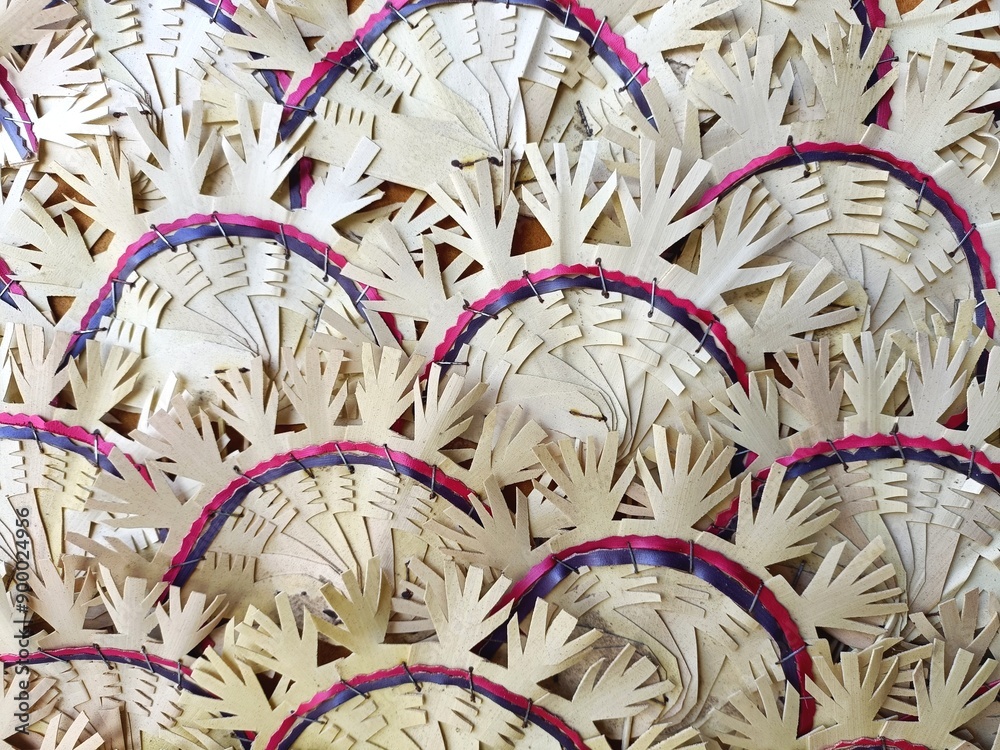 Horizontal pattern of overlapping fans made of dry palm fronds with cutout shapes