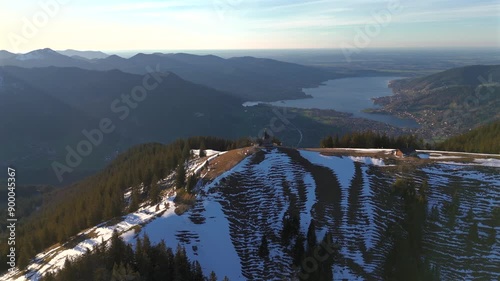 Kapelle Heilig Kreuz Rottach-Egern Tegernsee. Wallbergkapelle on mountain Wallberg overlooking lake Tegernsee and mountain range in sunny spring weather with snow at sunset. Chapel on peak of Alps.  photo