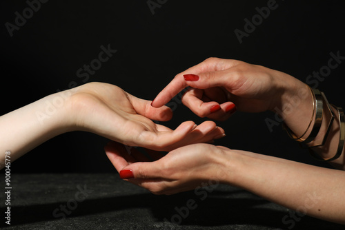 Photography Fortune teller reading lines on woman's palm at dark grey table, closeup