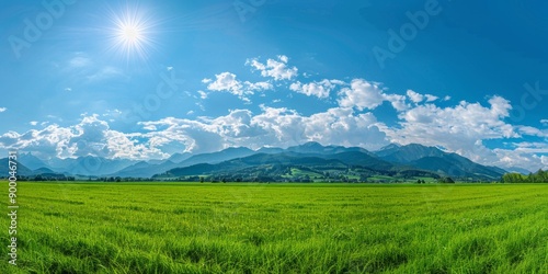 Breathtaking Panoramic Natural Landscape: Lush Green Meadow Under Vibrant Blue Sky with Fluffy Clouds and Majestic Mountains. Idyllic Scenery Perfect for Relaxation, Outdoor Adventure, and Environment © Da