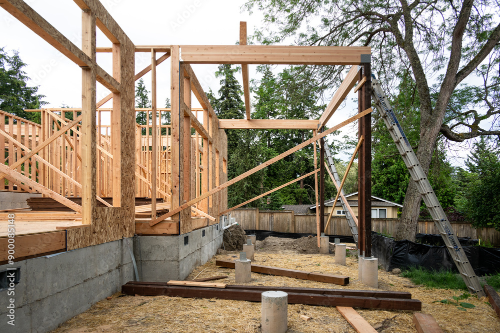 New house construction in residential neighborhood, job site detail of back of home foundation, wood framing, vertical support beams with aluminum extension ladders
New house construction in residential neighborhood, job site detail of back of home foundation, wood framing, vertical support beams with aluminum extension ladders