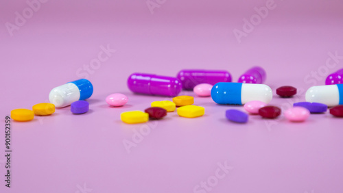 Multi-colored pills and capsules used in medical treatment are scattered on a pink background. Colorful pills and capsules. Healthcare and medical concept. Space for text.