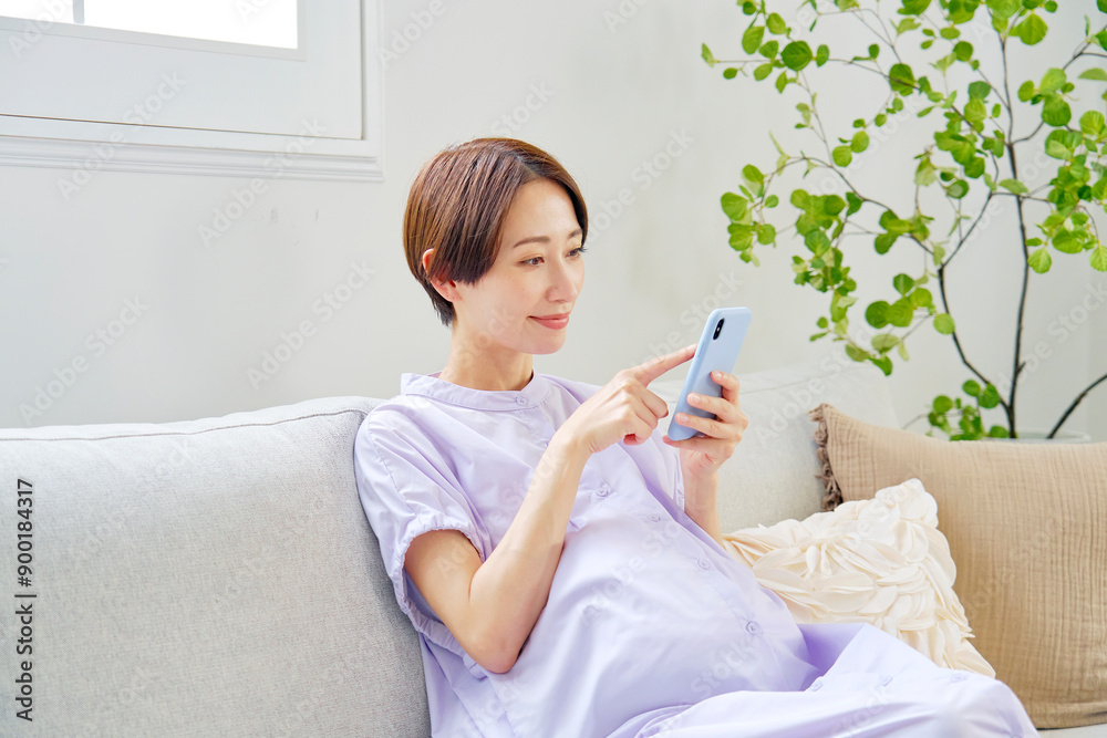 自宅でスマートフォンを使う高齢妊娠をした妊婦 自宅でスマートフォンを使う高齢妊娠をした妊婦