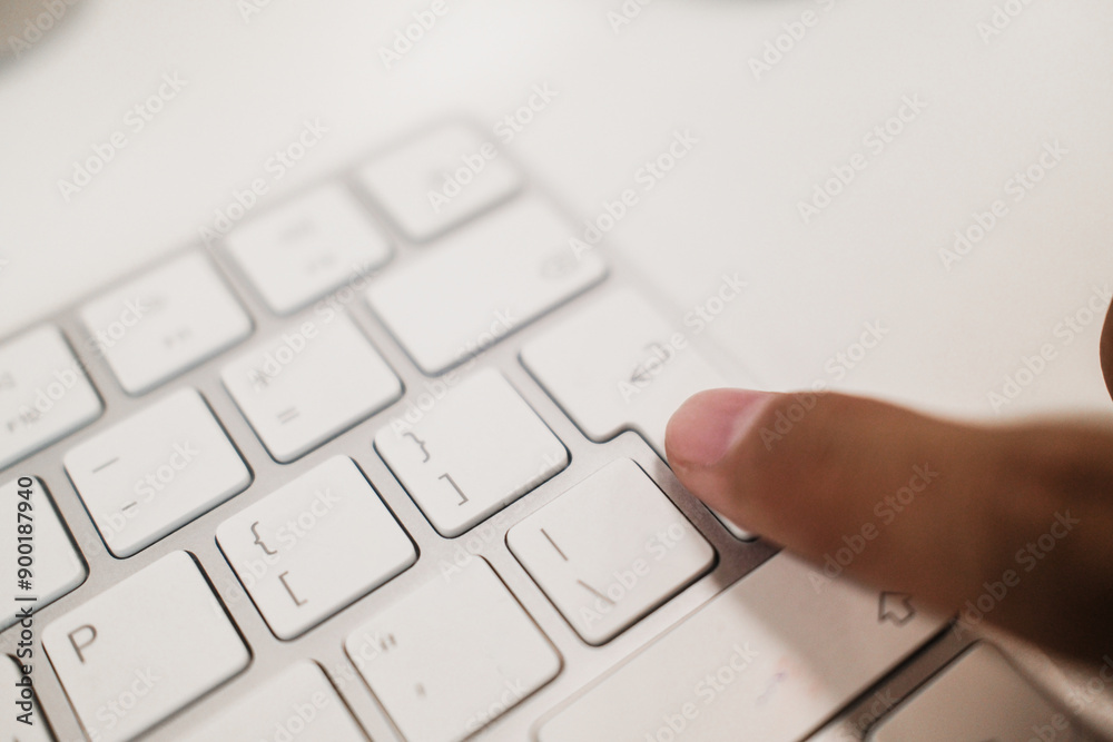 Finger on wireless keyboard enter button. Person's finger pressing submit button Finger on wireless keyboard enter button. Person's finger pressing submit button