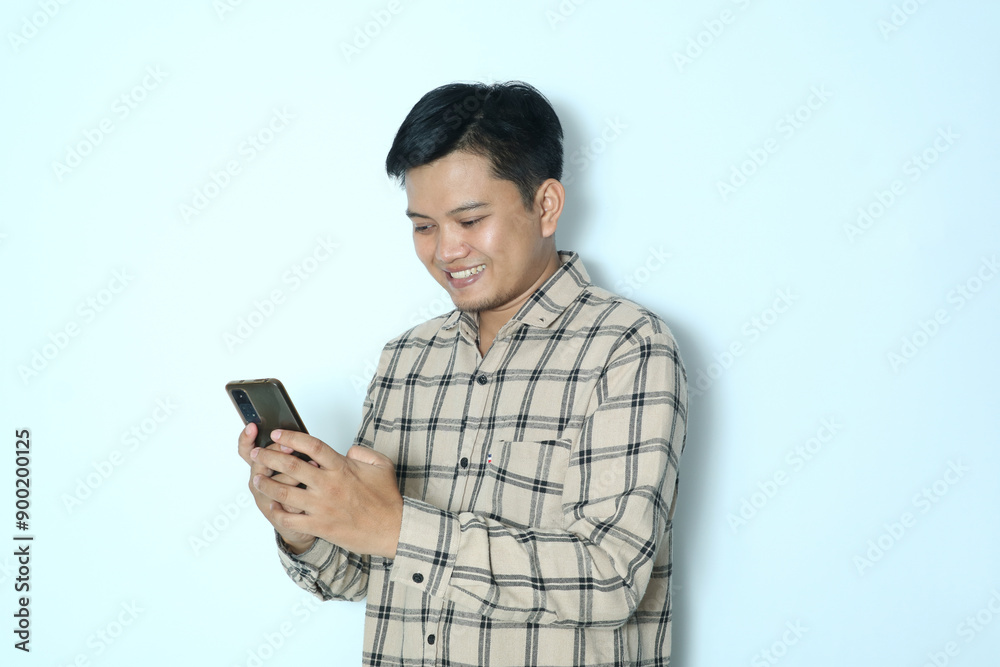 Young Asian man looking to his mobile phone. Wearing a cream flannel shirt Young Asian man looking to his mobile phone. Wearing a cream flannel shirt