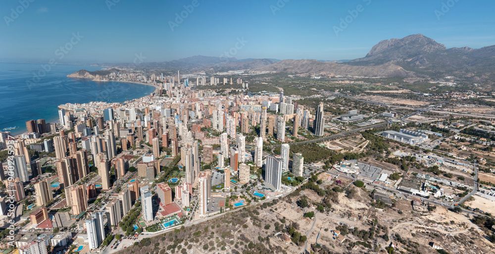 Extremely wide aerial drone panoramic photo of the city Benidorm in Spain showing the whole of the city with high rise buildings and hotels and a clear view of the ocean front on a sunny summer day