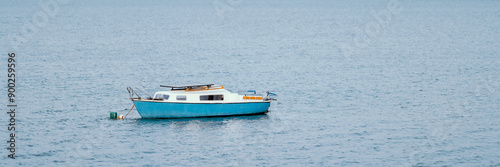 Obraz na płótnie A lonely old blue boat with orange elements moored on a lake far from the shore. w salonie